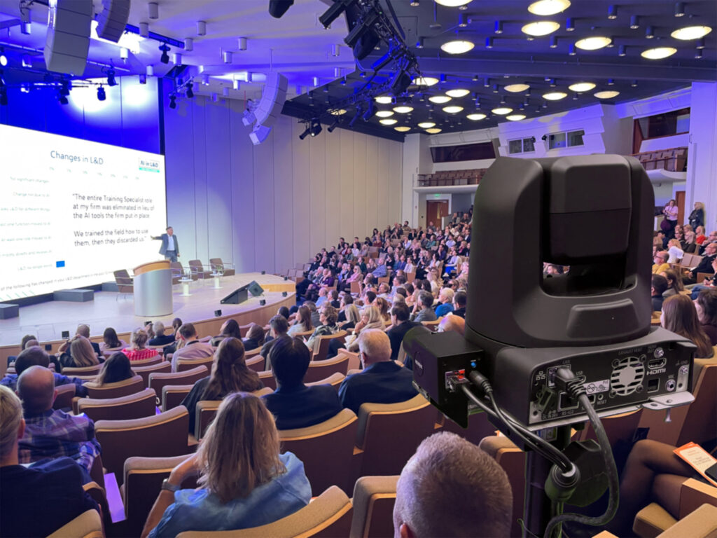 En robotkamera filmar en fullsatt konferenssal